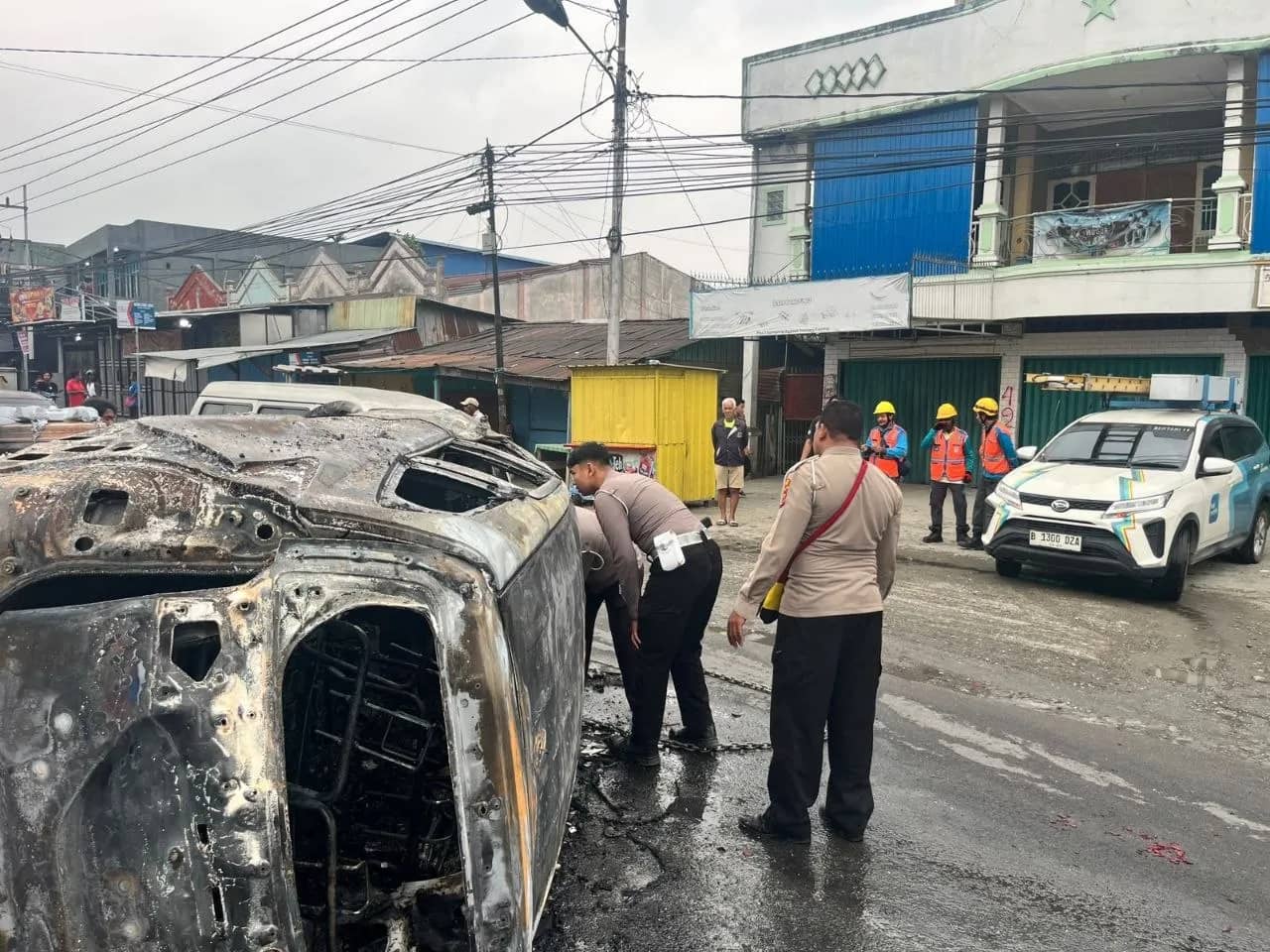 Polisi saat melakukan penanganan mobil terbakar di Jalan Raya Sentani