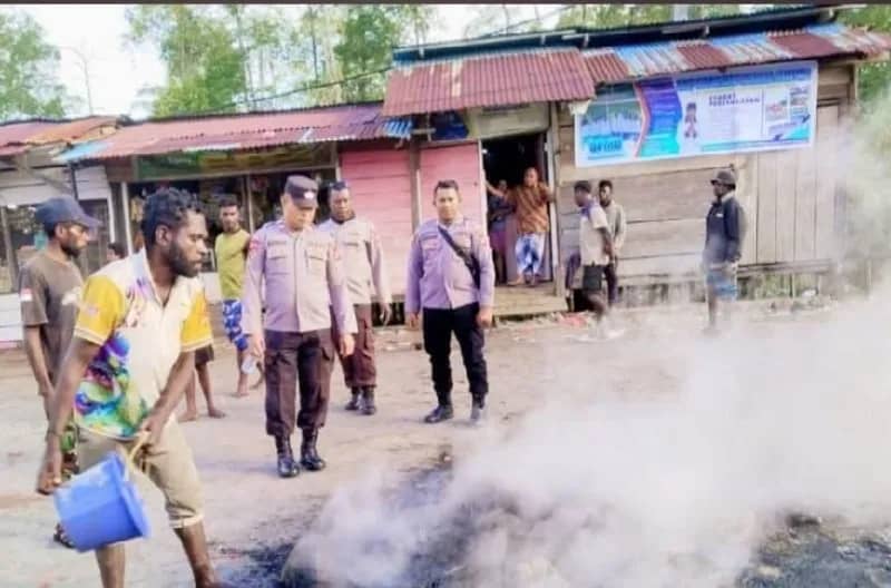 Nampak salahsatu warga menyiram api yang sebelumnya digunakan keluarga korban untuk melakukan pemalangan Jalan Pomako-Timika.