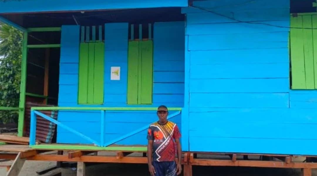 Ketua Pokja Kampung Akar Distrik Mimika Barat Tengah Isidorus Tanotani berpose di depan salah satu rumah yang pembangunannya menggunakan dana Pokja YPMAK, Sabtu (12/9/2026).