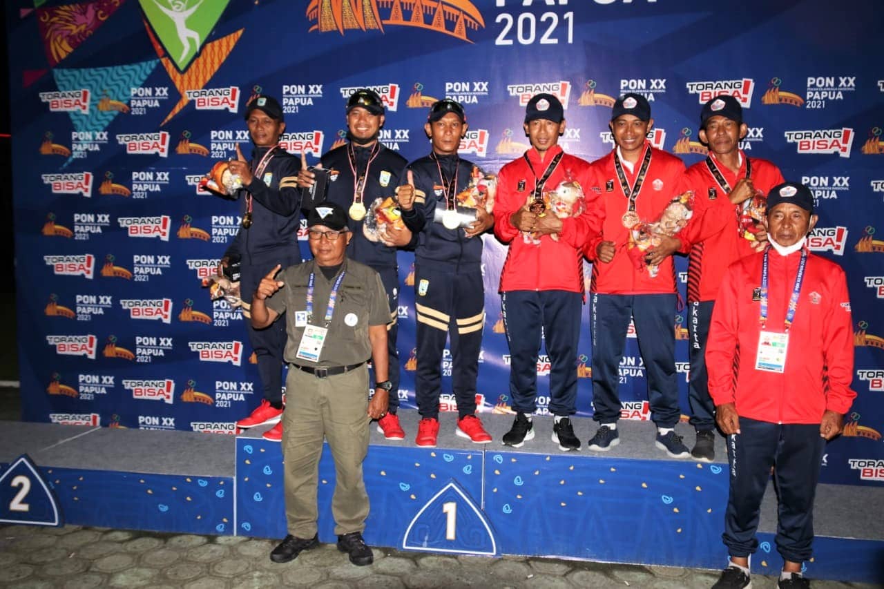 Tim Terjun Payung Papua Barat (Baju Biru) peraih mendali emas dan DKI Jakarta (Baju Merah) peraih mendali perunggu, saat mengikuti penyerahan untuk nomor kerjasama antar parasut di venue terjun payung, halaman Kantor Pusat Pemerintahan Kabupaten Mimika, Kamis (14/10/2021). Penyerahan mendali tidak diikuti Kontingen Kaltim yang sedang mengajukan banding ke Dewan Hakim PON XX terkait hasil penjurian. Foto: Saldi Hermanto/Humas PPM