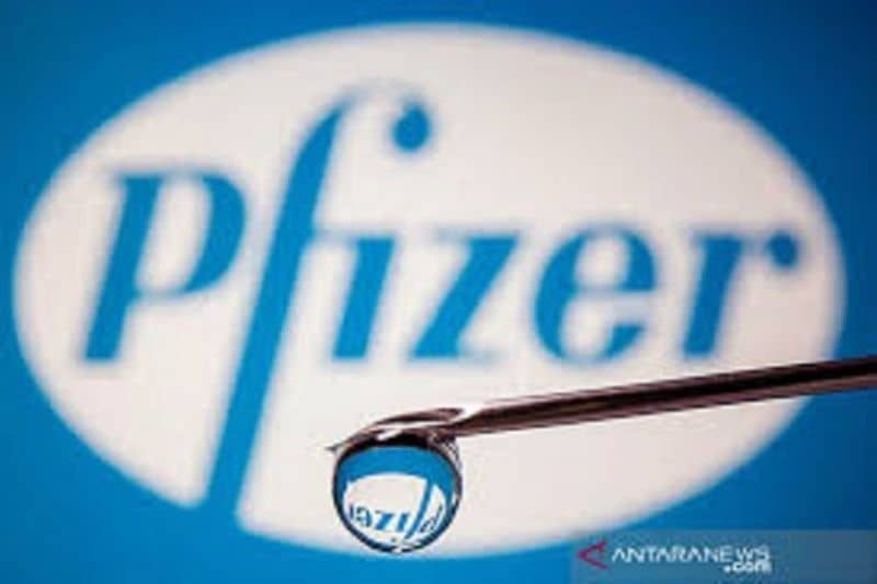 Logo Pfizer terefleksi pada tetesan cairan jarum suntik sebagai ilustrasi vaksin COVID-19.