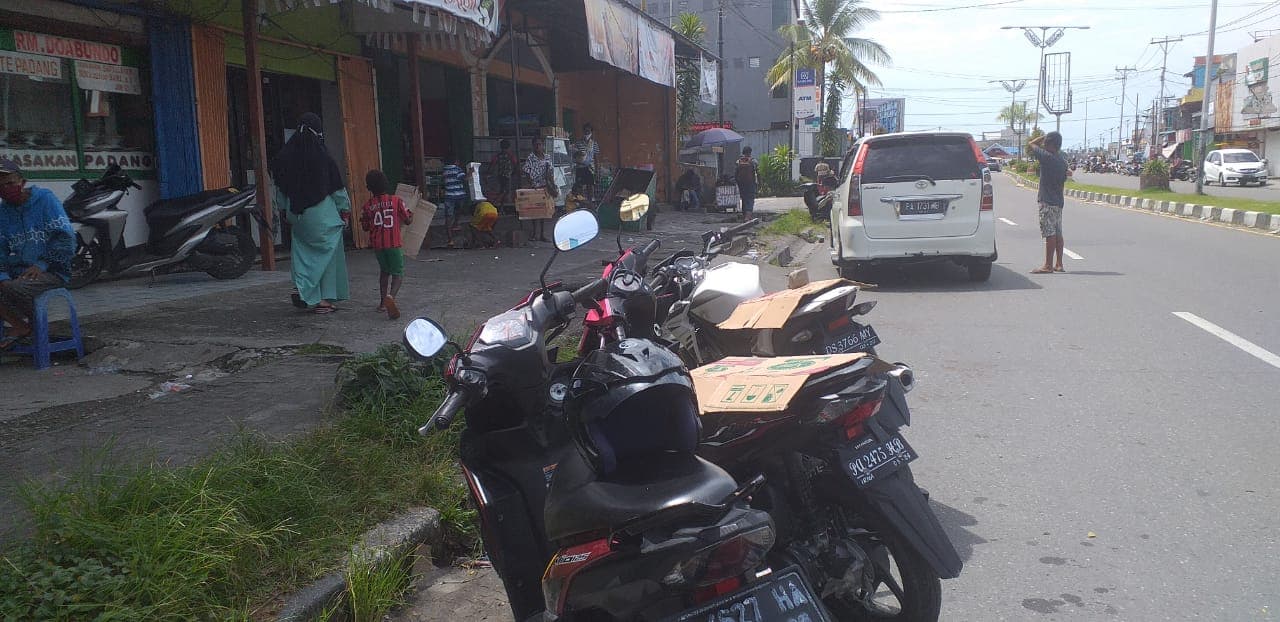 Para bocah jasa penutup motor menggunakan karton di jalan Yos Sudarso Timika
