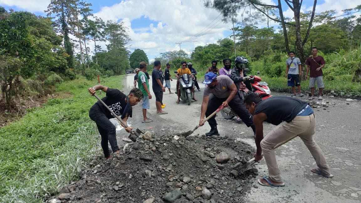 Aiptu Balthasar Fasse bersama sopir truk sedang kerja bakti timbun jalan.
