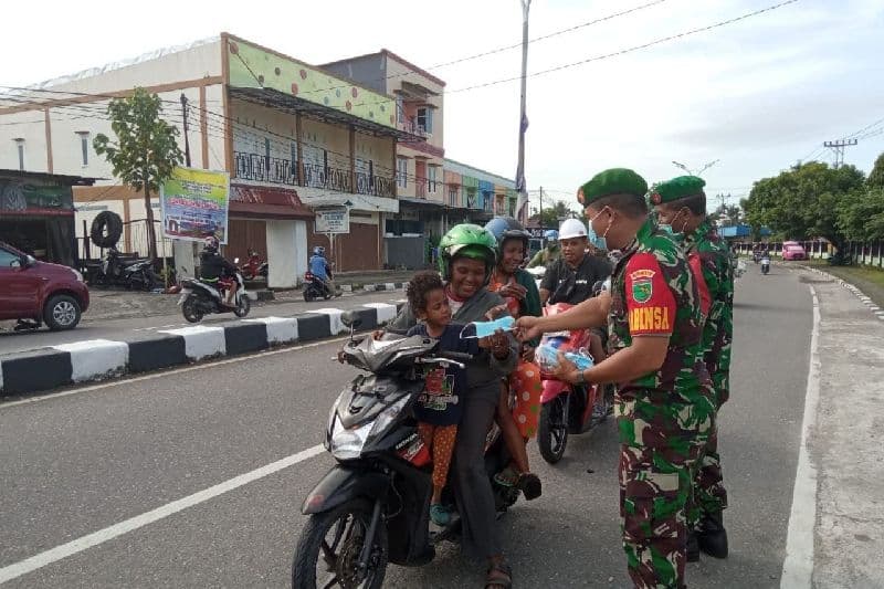 Personel TNI Koramil Mimika Pelda Mustajib memberikan edukasi prokes pengguna jalan dan membagikan masker.
