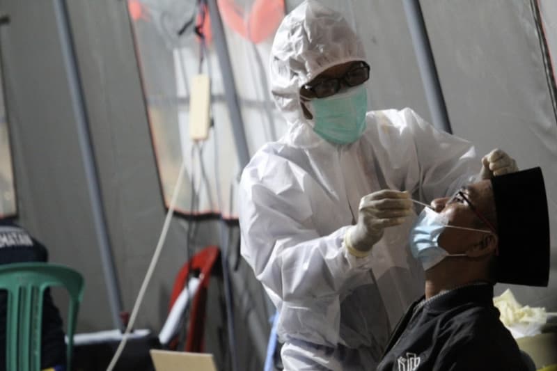 Tenaga kesehatan tengah melakukan pemeriksaan tes cepat antigen kepada masyarakat.