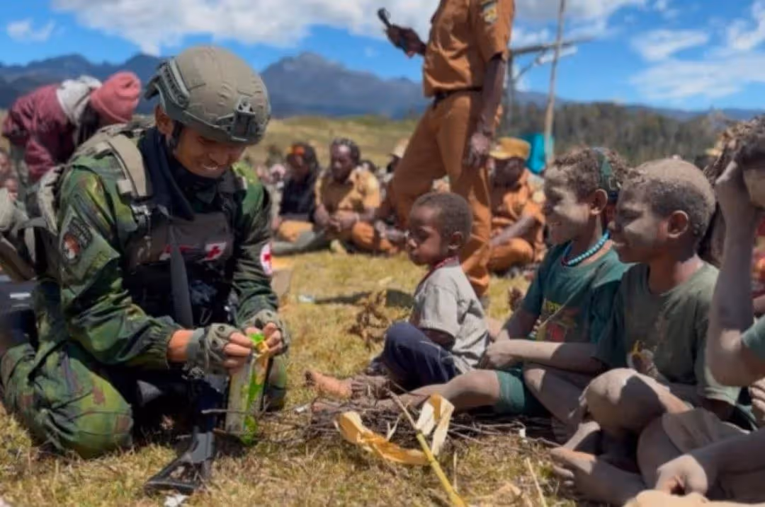 Personel Satgas Habema saat berinteraksi dengan anak-anak dalam penyaluran bantuan pangan di Kabupaten Puncak
