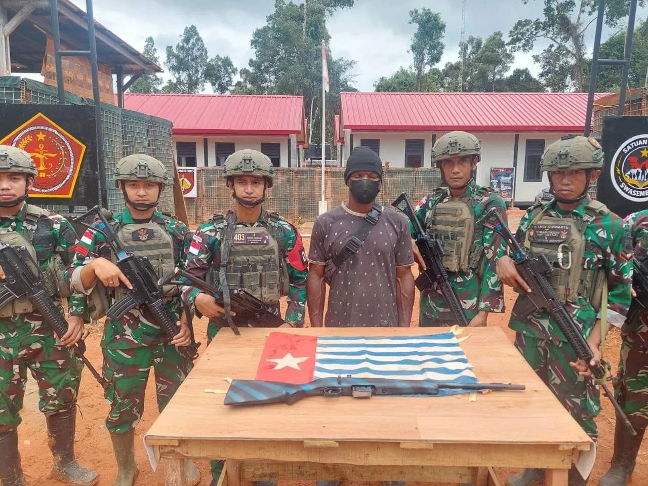 Personil Satgas TNI di Pos Perbatasan Indonesia–Papua Nugini berpose bersama Yujin Butiop usai penyerahan senpi rakitan dan bendera bintang kejora.
