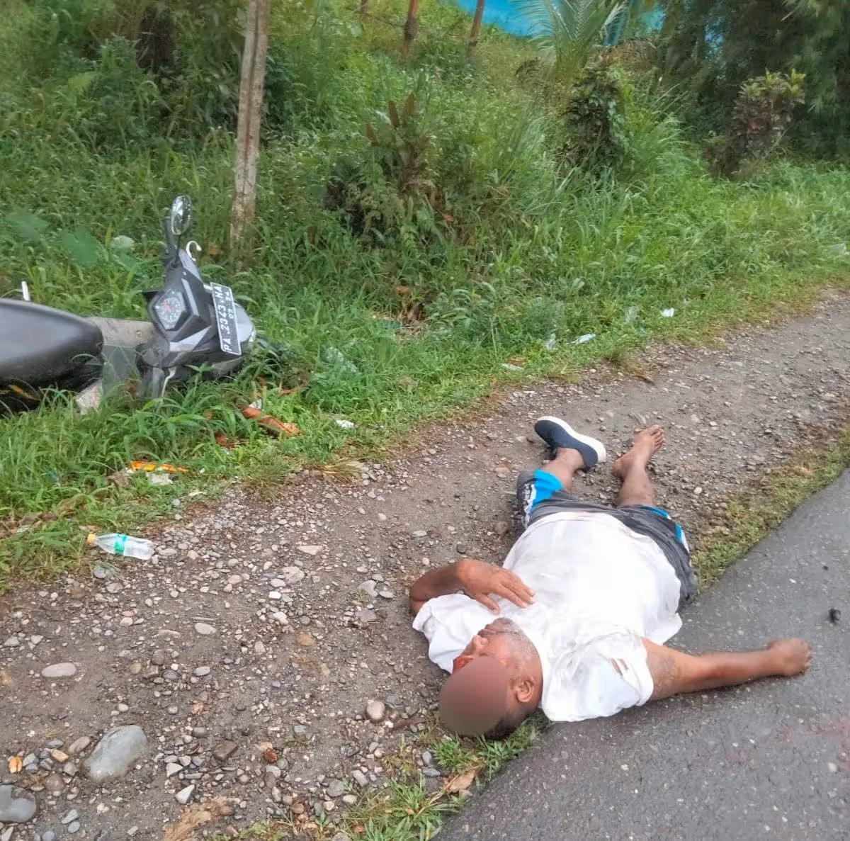 Seorang pria yang belum diketahui identitasnya terkapar di perempatan jalan Bandara Mozes Kilangin Timika usai terjatuh dari sepeda motor.