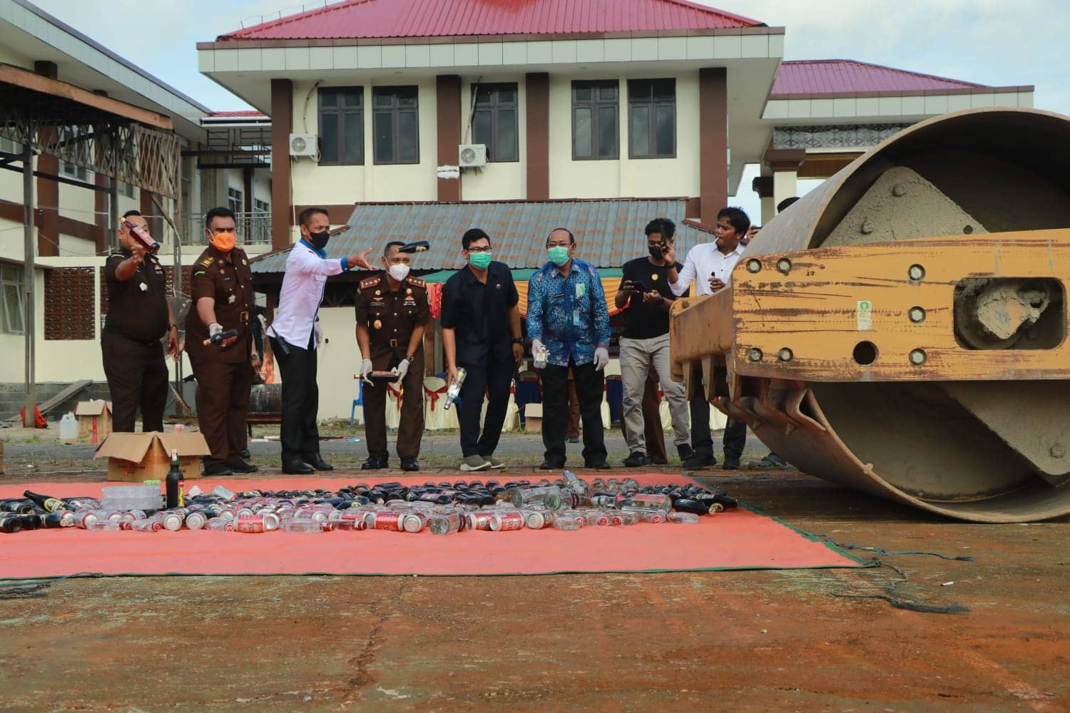Alat berat menggilas ribuan botol miras lokal.