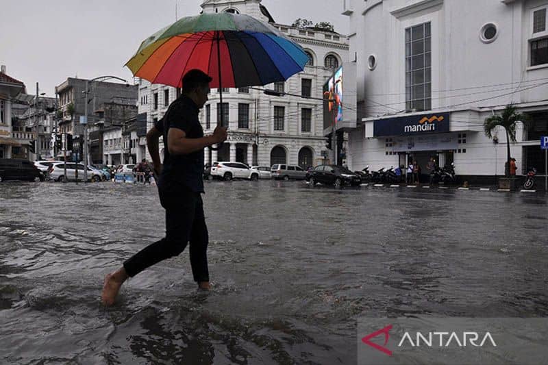 Ilustrasi - Seorang warga berjalan melintasi genangan air di Jalan Balaikota Medan, Sumatera Utara