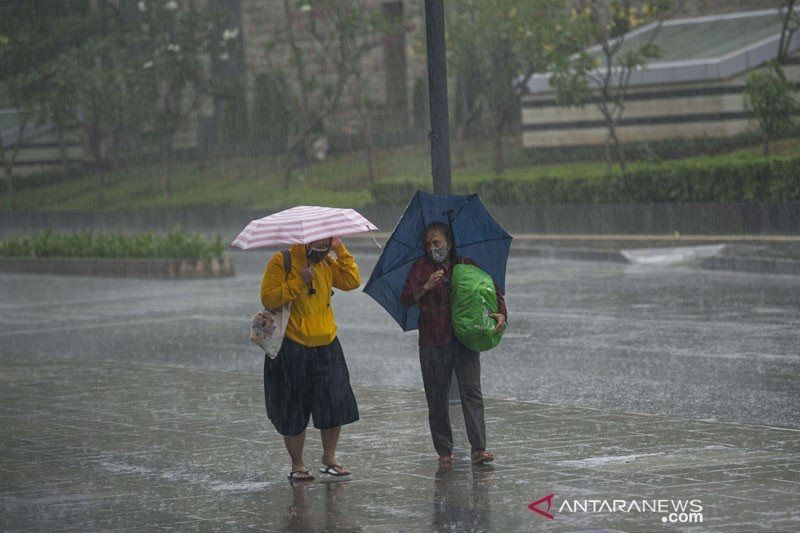Warga menggunakan payung untuk melindungi diri dari guyuran hujan di kawasan Stasiun MRT Dukuh Atas BNI, Jakarta.