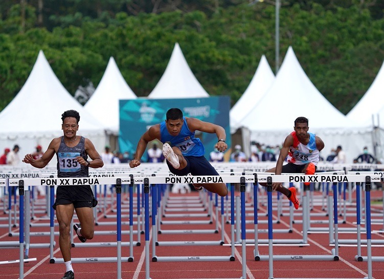 Atlet 110 Meter Gawang Putra 304 RIO MAHOLTRA (BIRU) asal Sumatera Selatan berhasil finis terdepan dengan catatan waktu 14.11 mengungguli Hirzan Rahmadon (14.33) diposisi 2. 304 RIO MAHOLTRA (BIRU) berhasil meraih medali emas di lari 110 meter gawang putra. Timika, (5/10/2021). FOTO: HUMAS PPM/ Fernando Rahawarin