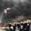 Polisi Palestina berjaga dekat ban yang dibakar oleh demonstran di kamp pengungsian Jalazoun dekat kota Ramallah, Tepi Barat.