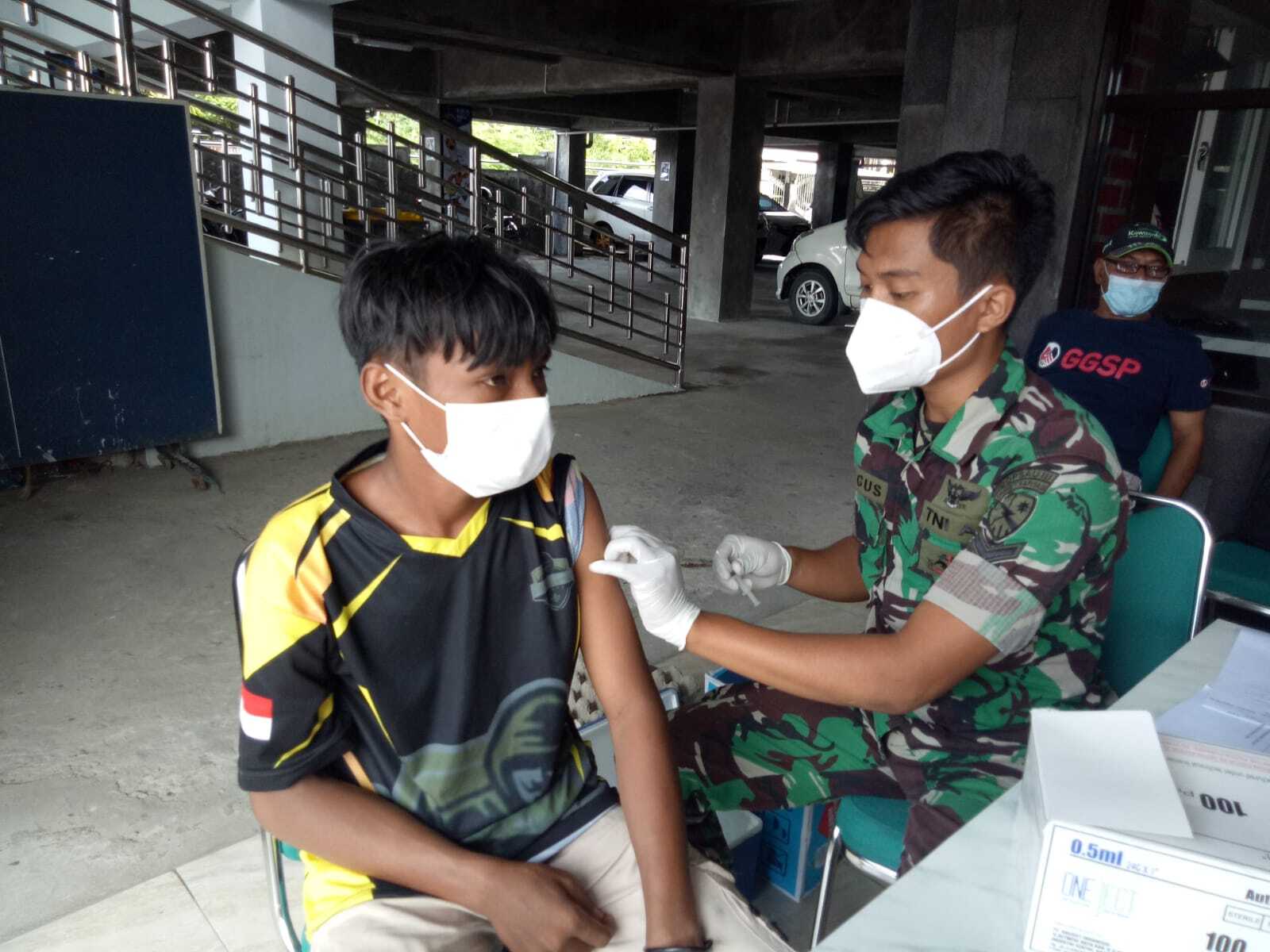 Anggota TNI sedang menyuntikkan vaksin kepada salahsatu warga.