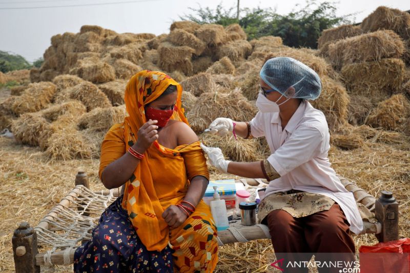 Jabuben Bharwad, 30 tahun, menerima dosis vaksin COVISHIELD, vaksin penyakit virus corona (COVID-19) yang diproduksi oleh Serum Institute of India, saat bekerja di lapangan saat program vaksinasi dari pintu ke pintu di Desa Mahijada, pinggiran Kota Ahmedabad, India, Rabu (15/12/2021).