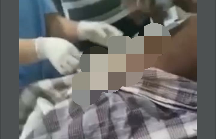 Petugas medis sedang mengeluarkan benda sejenis kain dari perut korban.