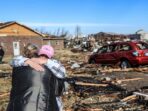 Irene Noltner menghibur Jody O'Neill di luar The Lighthouse, tempat perlindungan wanita dan anak-anak yang dihancurkan oleh tornado bersama dengan sebagian besar pusat kota Mayfield, Kentucky, AS, Sabtu (11/12/2021).