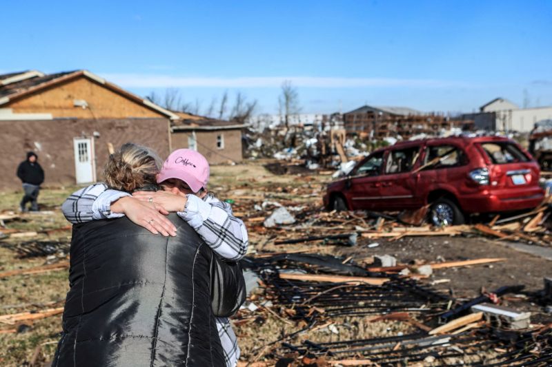 Irene Noltner menghibur Jody O'Neill di luar The Lighthouse, tempat perlindungan wanita dan anak-anak yang dihancurkan oleh tornado bersama dengan sebagian besar pusat kota Mayfield, Kentucky, AS, Sabtu (11/12/2021).