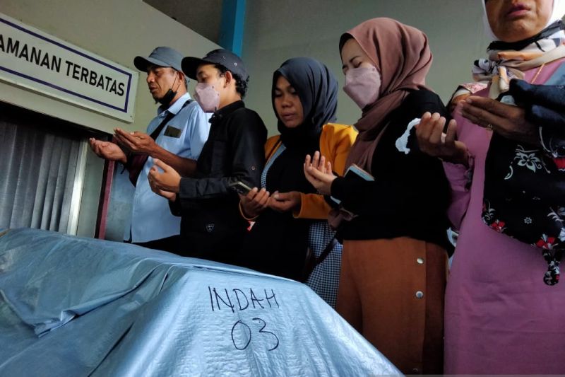 Keluarga berdoa di samping peti jenazah DJ Indah Cleo, salah satu korban aksi pembakaran karaoke di Kota Sorong, di Bandara Domine Eduard Osok Kota Sorong, Provinsi Papua Barat, Minggu (30/1/2022).