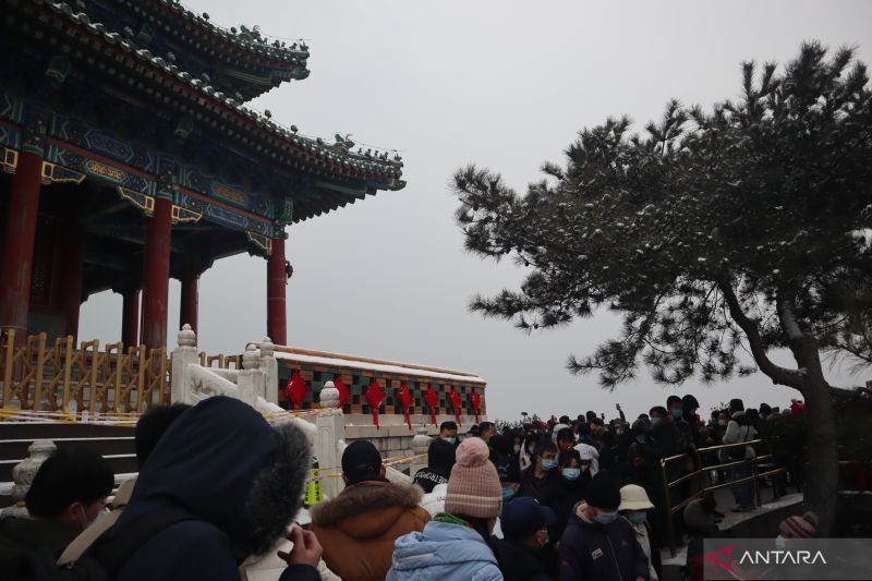 Para pengunjung memadati puncak bukit Jingshan, Beijing, China, Sabtu (22/1), saat turun salju. Dari puncak Jingshan inilah, pemandangan Kota Beijing dapat terlihat dengan jelas.