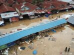 Warga berjalan menembus banjir di Pasar Youtefa Abepura, Jayapura, Papua, Jumat (7/1/2022).