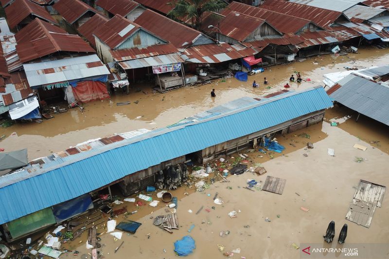 Warga berjalan menembus banjir di Pasar Youtefa Abepura, Jayapura, Papua, Jumat (7/1/2022).