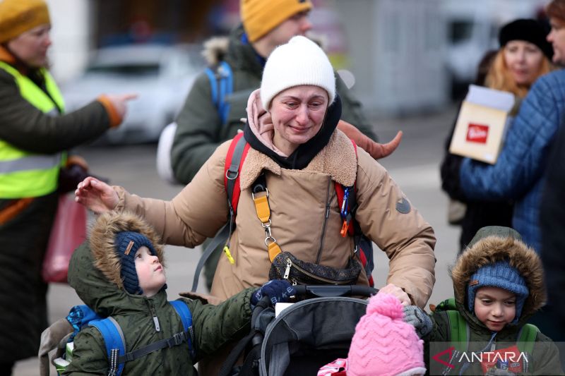 Warga Ukraina membawa anak-anaknya melintasi perbatasan di Siret, Rumania, Senin (28/2/2022).