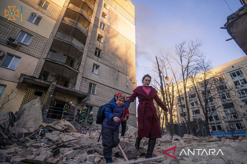 Seorang wanita dengan seorang anak dievakuasi dari sebuah bangunan tempat tinggal yang rusak akibat penembakan, saat serangan Rusia di Ukraina