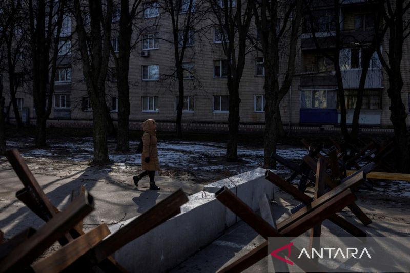 Seorang wanita berjalan melewati bangunan pertahanan untuk menghalangi laju kendaraan Rusia saat serangan di Ukraina berlanjut, di Brovary dekat Kyiv, Ukraina, Jumat (11/3/2022)