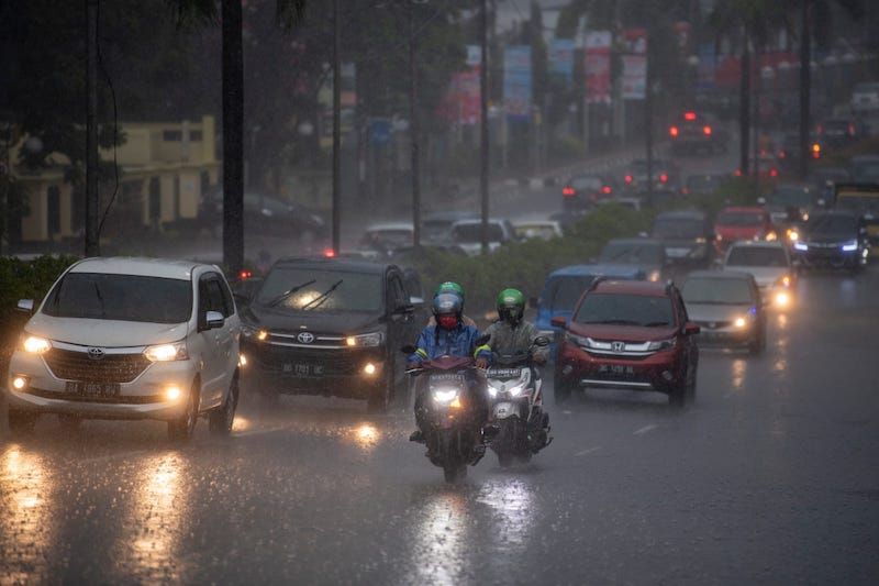Pengendara menerobos hujan lebat di jalan raya Kota Palembang, Sumatera Selatan.