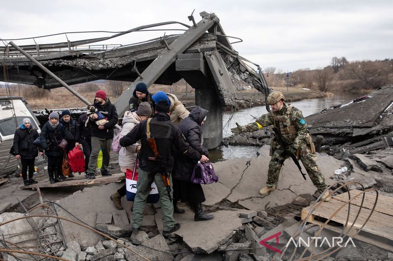 Orang-orang melarikan diri di dekat jembatan yang hancur untuk menyeberangi Sungai Irpin saat invasi Rusia ke Ukraina berlanjut, di Irpin di luar Kyiv, Ukraina, Rabu (9/3/2022)