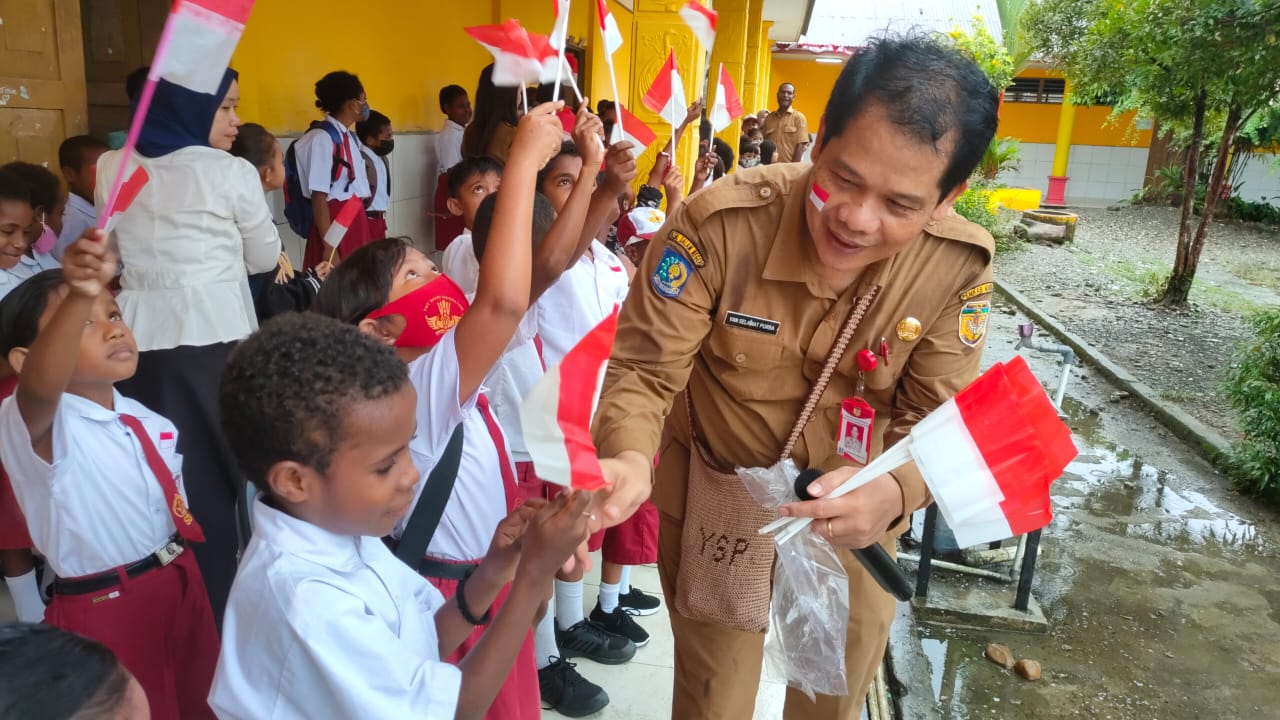 Foto: Febri Kepala Badan Kesbangpol Mimika, Yan Selamat Purba saat membagikan Bendera Merah Putih disalahsatu sekolah dasar di Timika.