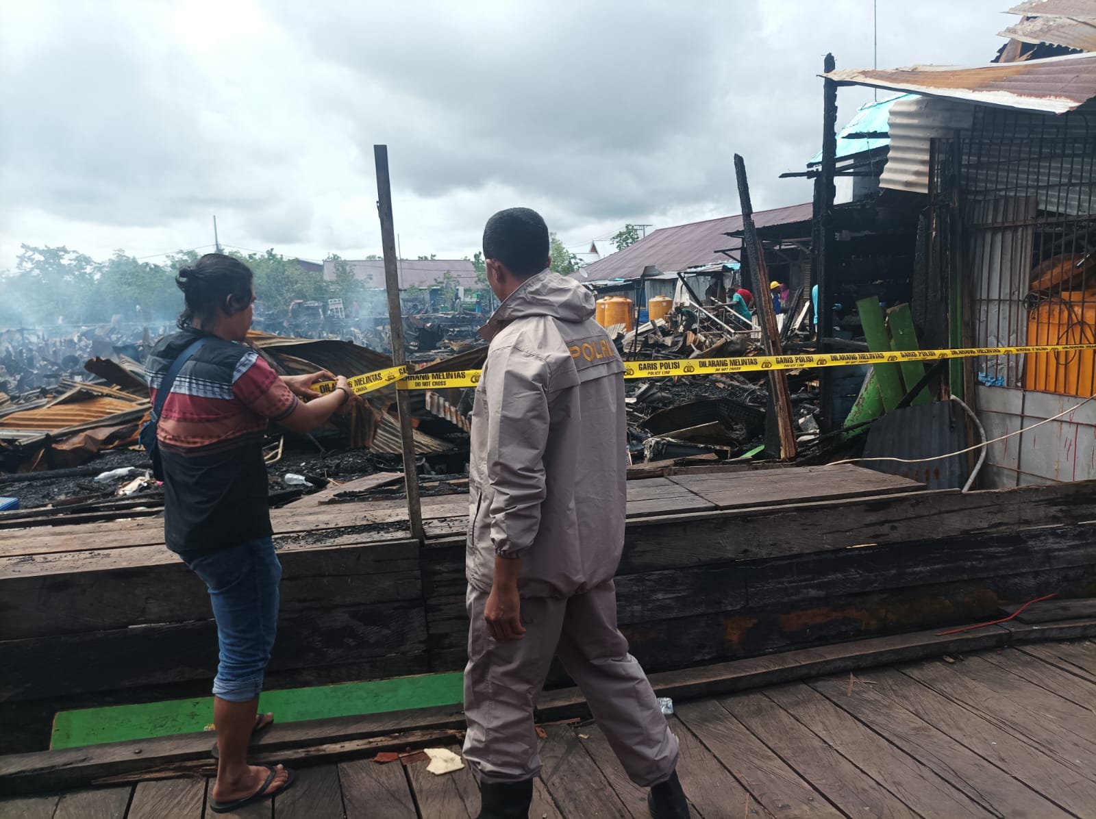 Foto: Istimewa Nampak penyidik dari Polres Asmat saat memasang garis polisi di lokasi yang diduga menjadi titik awal api yang menghanguskan Pasar Dolog di Kabupaten Asmat.